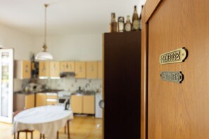 Une cuisine avec des meubles de rangement en bois, une table et un luminaire suspendu.