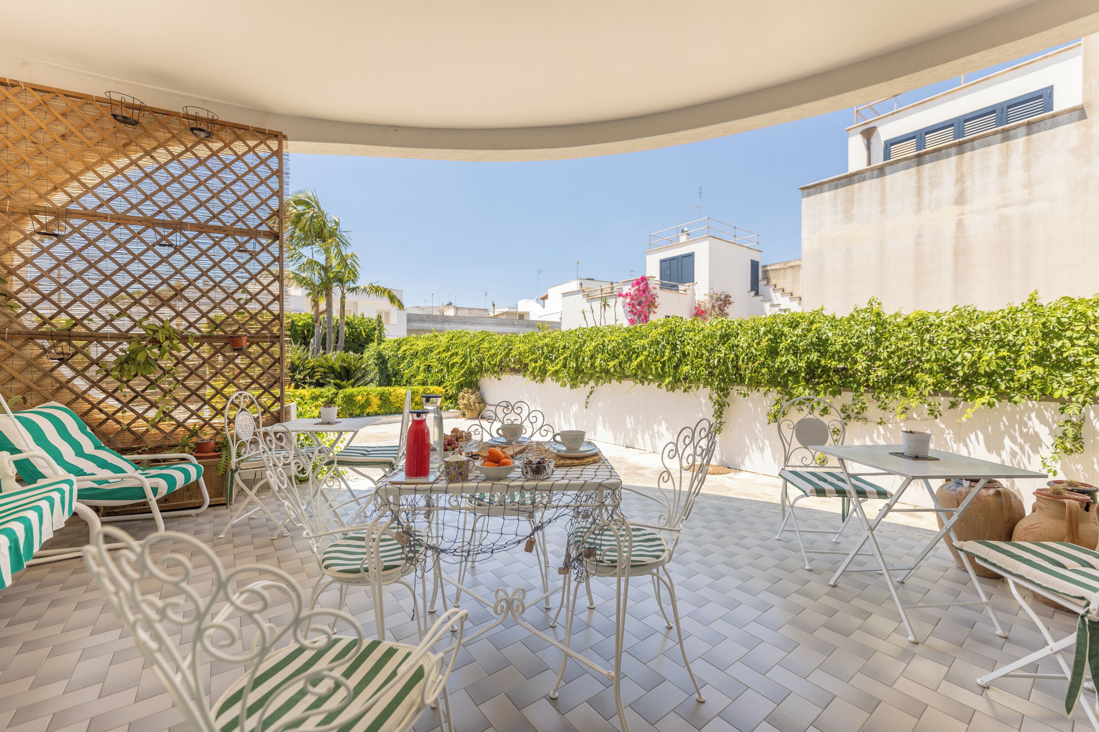 An outdoor patio with a table set for dining, surrounded by chairs and a sofa.