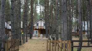 A cabin surrounded by tall trees, with a wooden fence in the foreground. - Ekodom (Voropaiv)