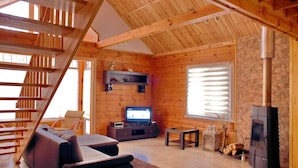 A wooden interior with a staircase, a sofa, a television, and a fireplace. - Ekodom (Voropaiv)