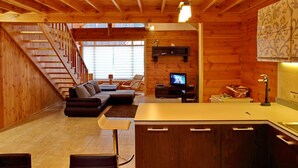 A wooden interior with a staircase, living room, kitchen, and a TV. - Ekodom (Voropaiv)