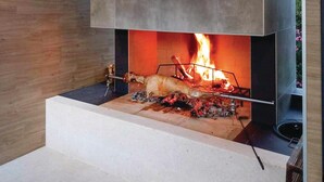 Una parrilla moderna para exteriores con fuego ardiendo debajo de una cubierta metálica grande.