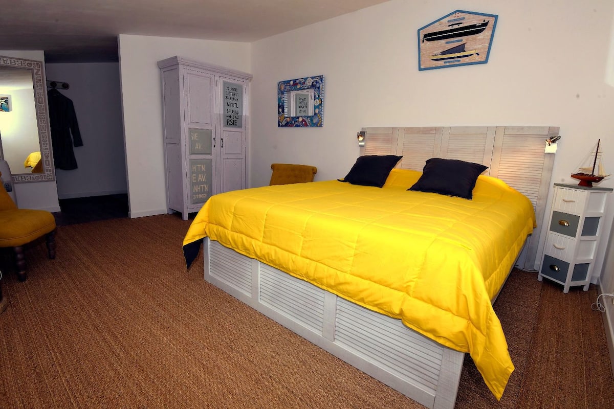 A bedroom with a bed, a wardrobe, a chair, and a dresser.