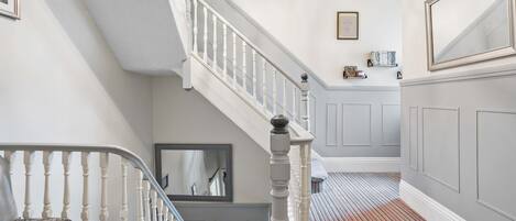 A staircase with white balusters, a patterned bench, and a striped carpet.