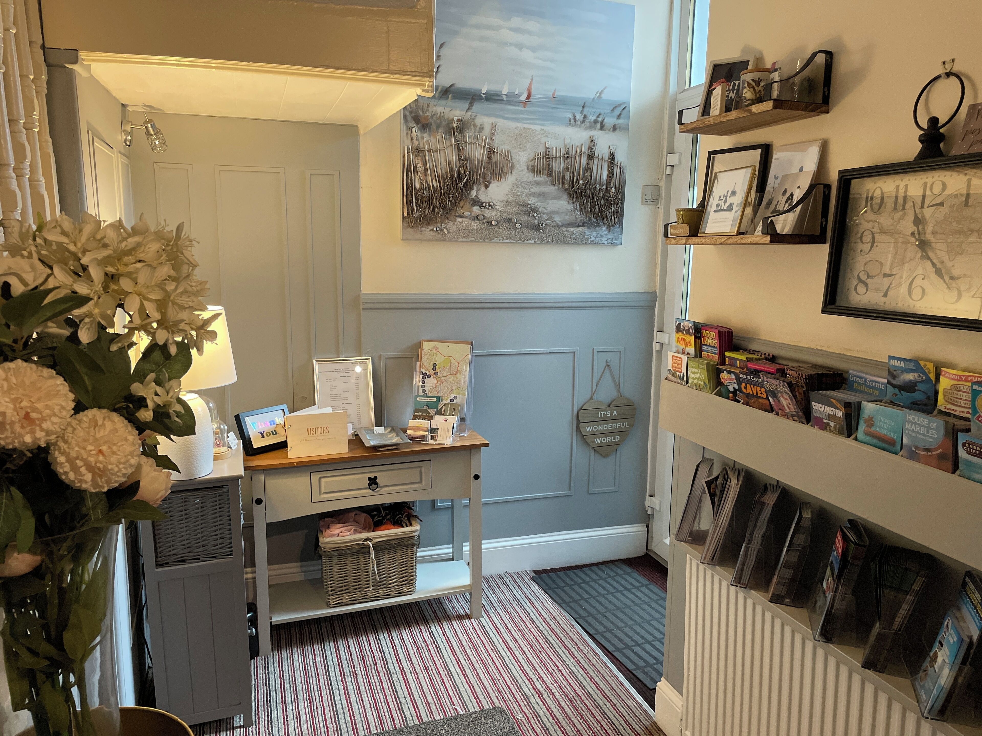 A reception desk with a map, a framed welcome sign, and a wall with framed pictures and a bookshelf with books.