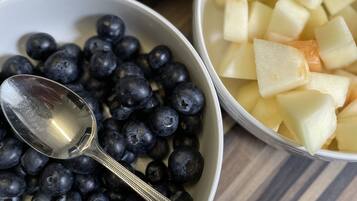 Drie schalen fruit met lepels op een tafel.