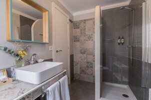 Un baño con un lavamanos grande, espejo, ducha y paredes de azulejos.