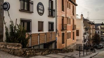 A building with a sign for 'rooms viva bar' and a stone wall with plants.