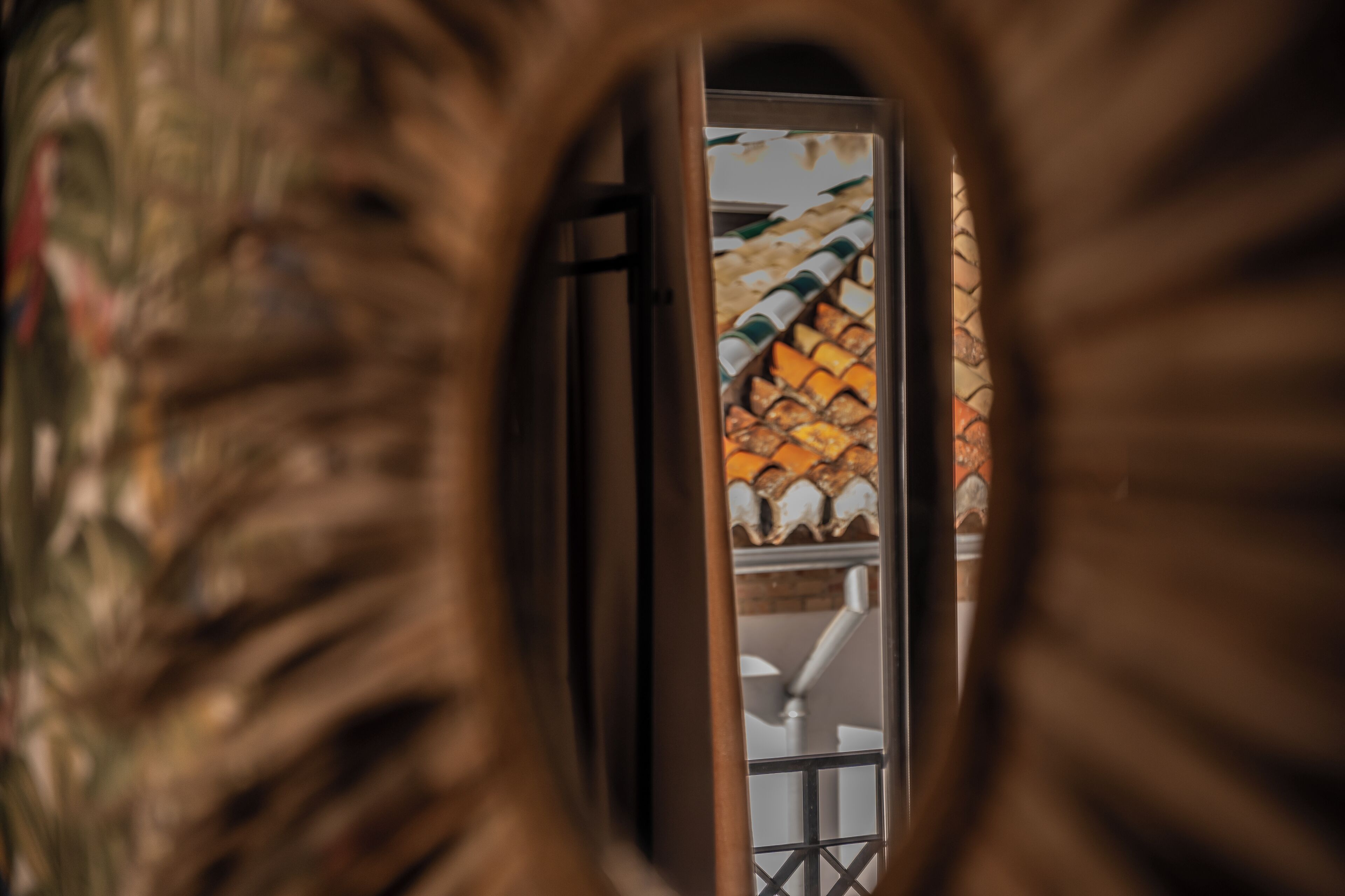 A view through a decorative frame with a tiled roof and a white railing.