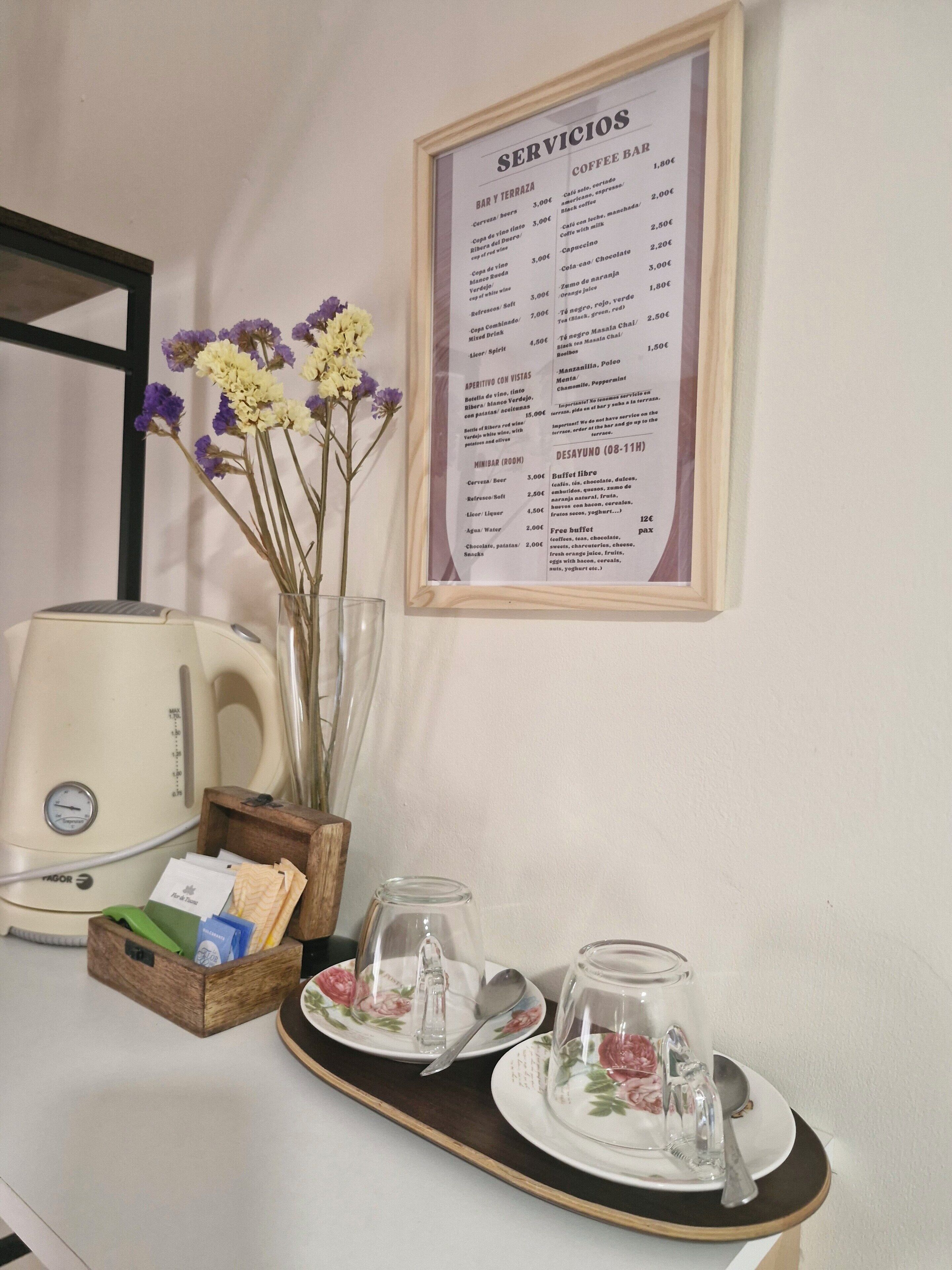 A breakfast setup with a menu, a coffee maker, and a tray with cups and a teapot.