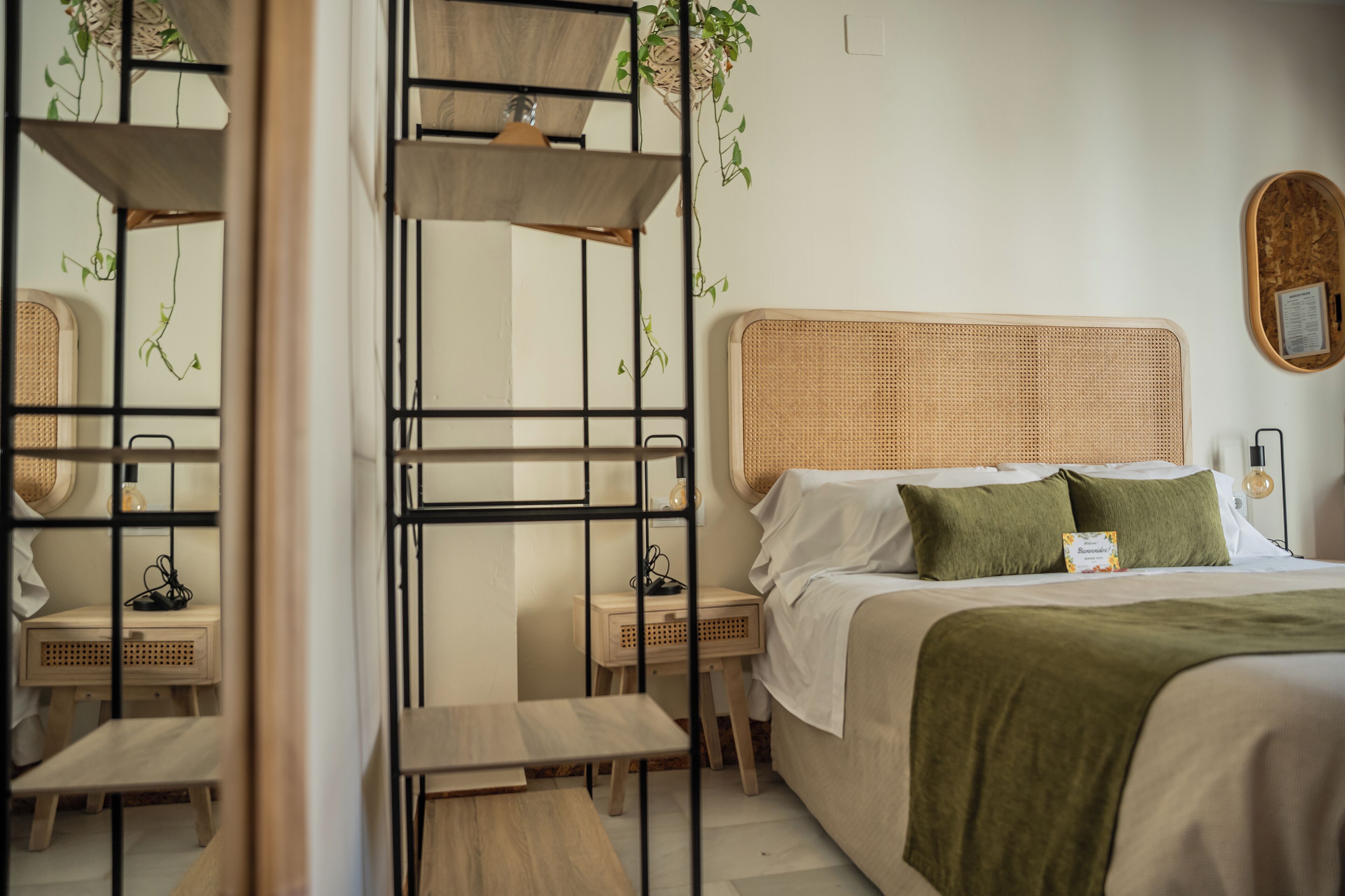 Quarto bem organizado com cama, mesas de cabeceira e uma planta pendurada.