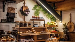 A bakery counter with various baked goods, a coffee machine, and a display of fruits and vegetables.