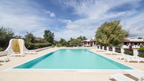 A rectangular swimming pool with white lounge chairs and a slide on one side. - White Sand Residence (Olbia)
