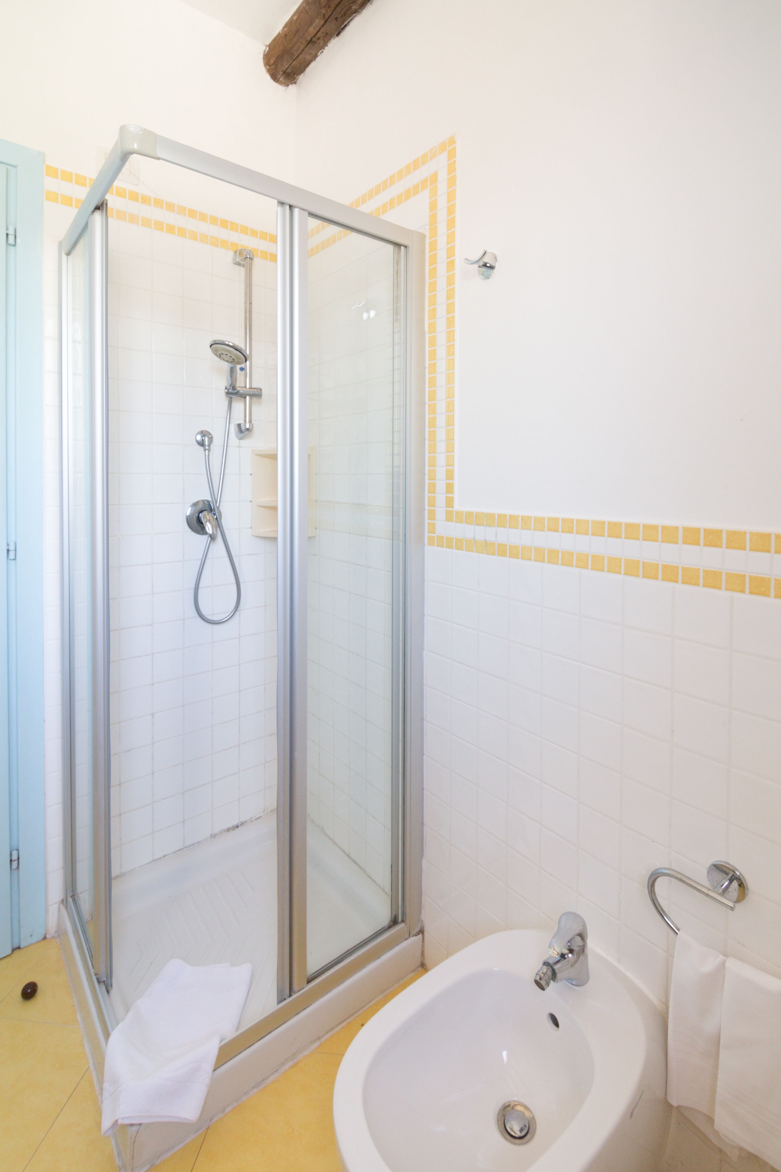 Un baño con ducha de mampara de vidrio, un lavabo blanco y una puerta azul.