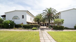 A white building with a sign reading "White Sand" and a paved pathway leading to the entrance. - White Sand Residence (Olbia)