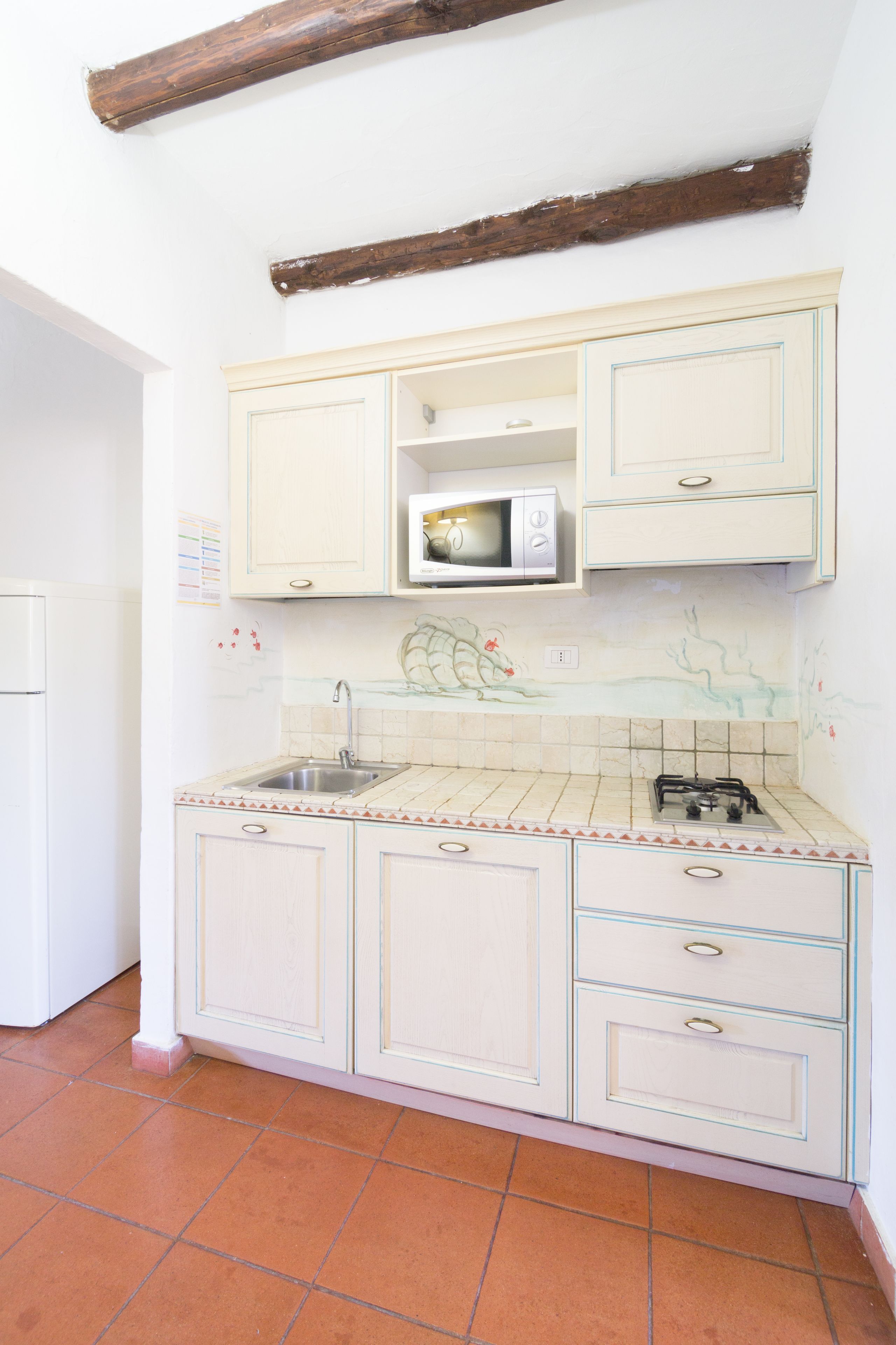 Una cocina con armarios blancos, un microondas y una estufa a gas.