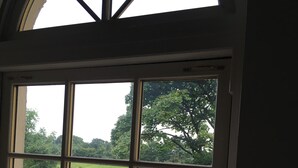 A view through a window of a room with a tiled patio, potted plants, and a chair. - The Rocks Bed & Breakfast (Crumlin)