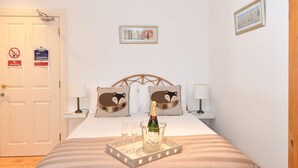 A neatly arranged bedroom with a bed, bedside lamps, a bottle of champagne, and a tray. - The Rocks Bed & Breakfast (Crumlin)