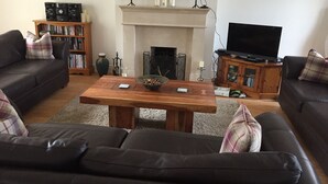 A living room with a fireplace, a television, a bookshelf, and a sofa. - The Rocks Bed & Breakfast (Crumlin)
