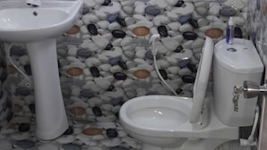 A bathroom with a white sink, toilet, and bidet, tiled with a pebbled pattern and a sky-like design on the wall. - Hotel Blue Moon (Dambulla)