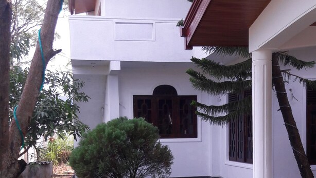 A white building with a covered porch, a small tree, and a grassy yard. - Hotel Blue Moon (Dambulla)