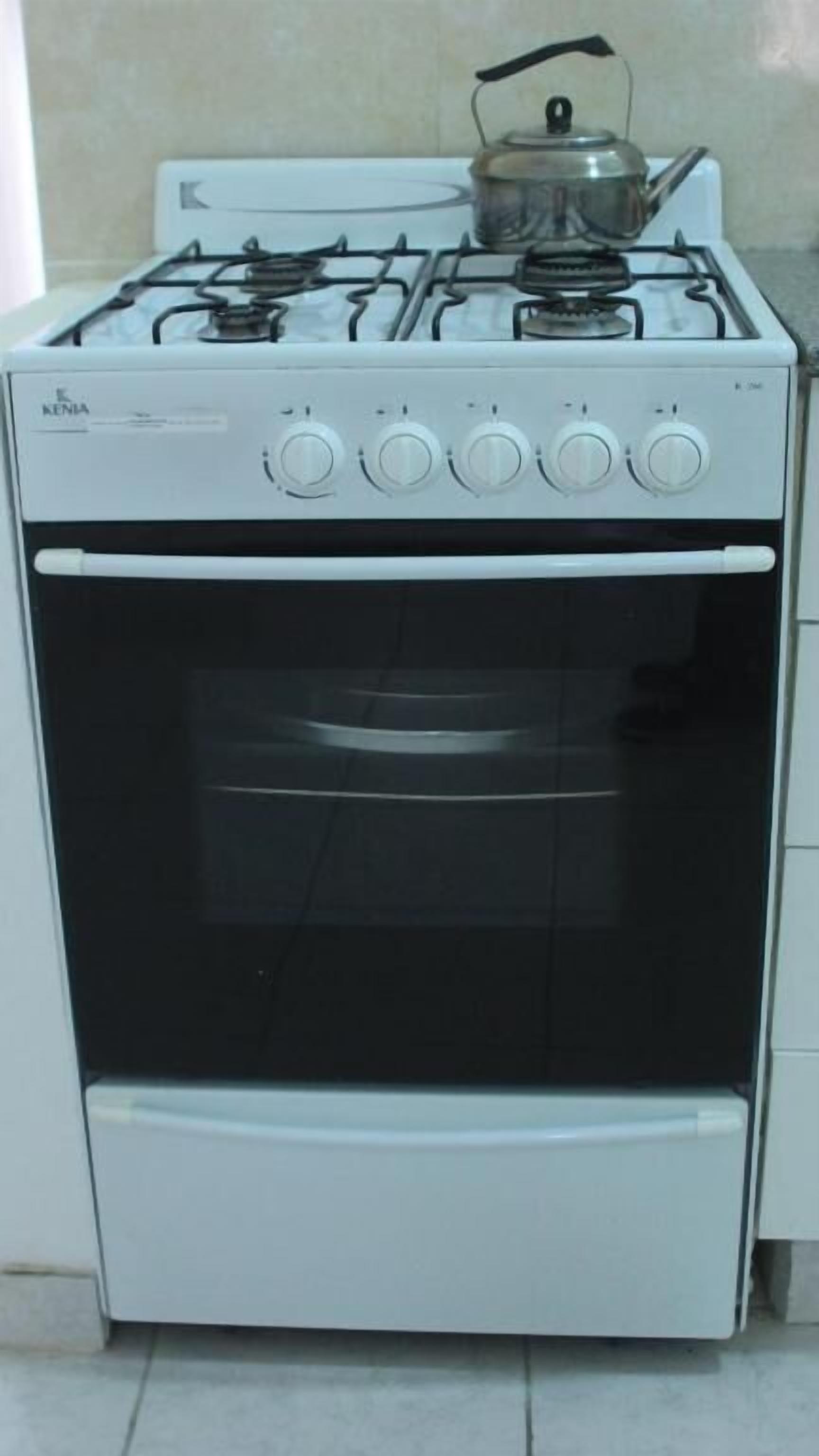 Una estufa Kenia blanca con un hervidor encima y un horno integrado debajo.
