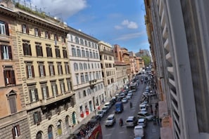 Vista de la calle con edificios históricos, coches aparcados y cielo despejado.