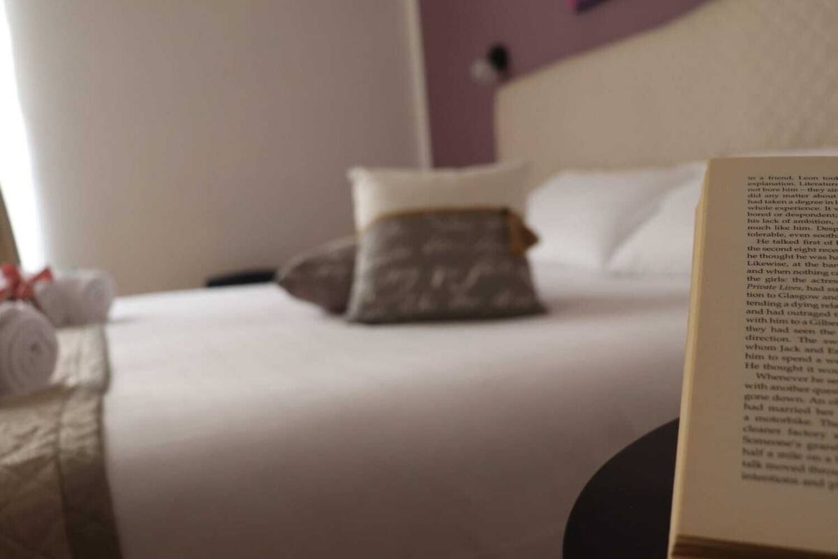 A neatly made bed with white linens and a single decorative pillow.