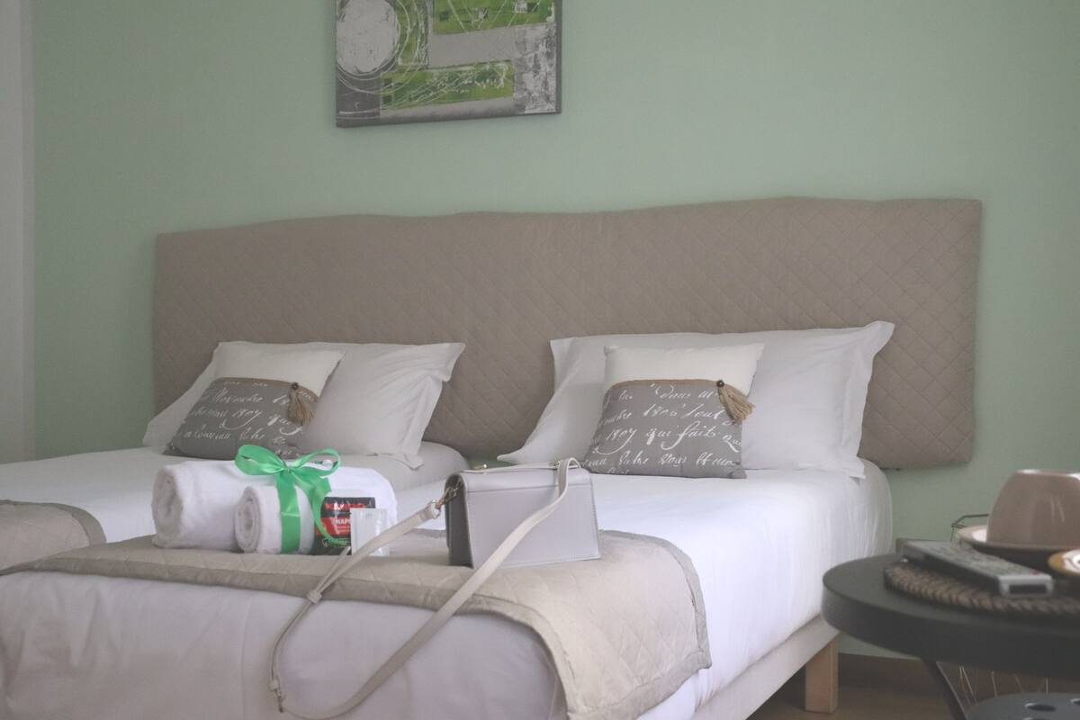 A hotel room with two beds, a round table, and a painting on the wall.