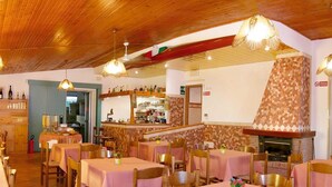 Un restaurant avec des tables et des chaises en bois, un coin bar et une cheminée.