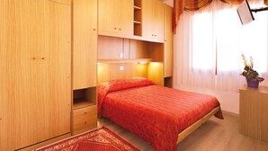 Une chambre à coucher avec un lit, une armoire en bois et une petite table sur laquelle est posée une plante.
