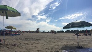 Une plage avec des parasols et des chaises longues.