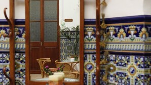 Una silla de madera, un espejo, una mesita y una planta decorativa.