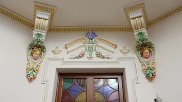 Una stanza con decorazioni elaborate alle pareti, una porta in legno e una telecamera di sicurezza.
