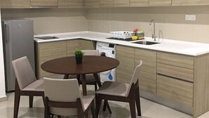 Une cuisine moderne avec une table de salle à manger ronde, quatre chaises et un lave-linge encastré.