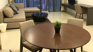Un salon moderne avec une table à manger ronde, un canapé beige et un téléviseur posé sur un meuble.