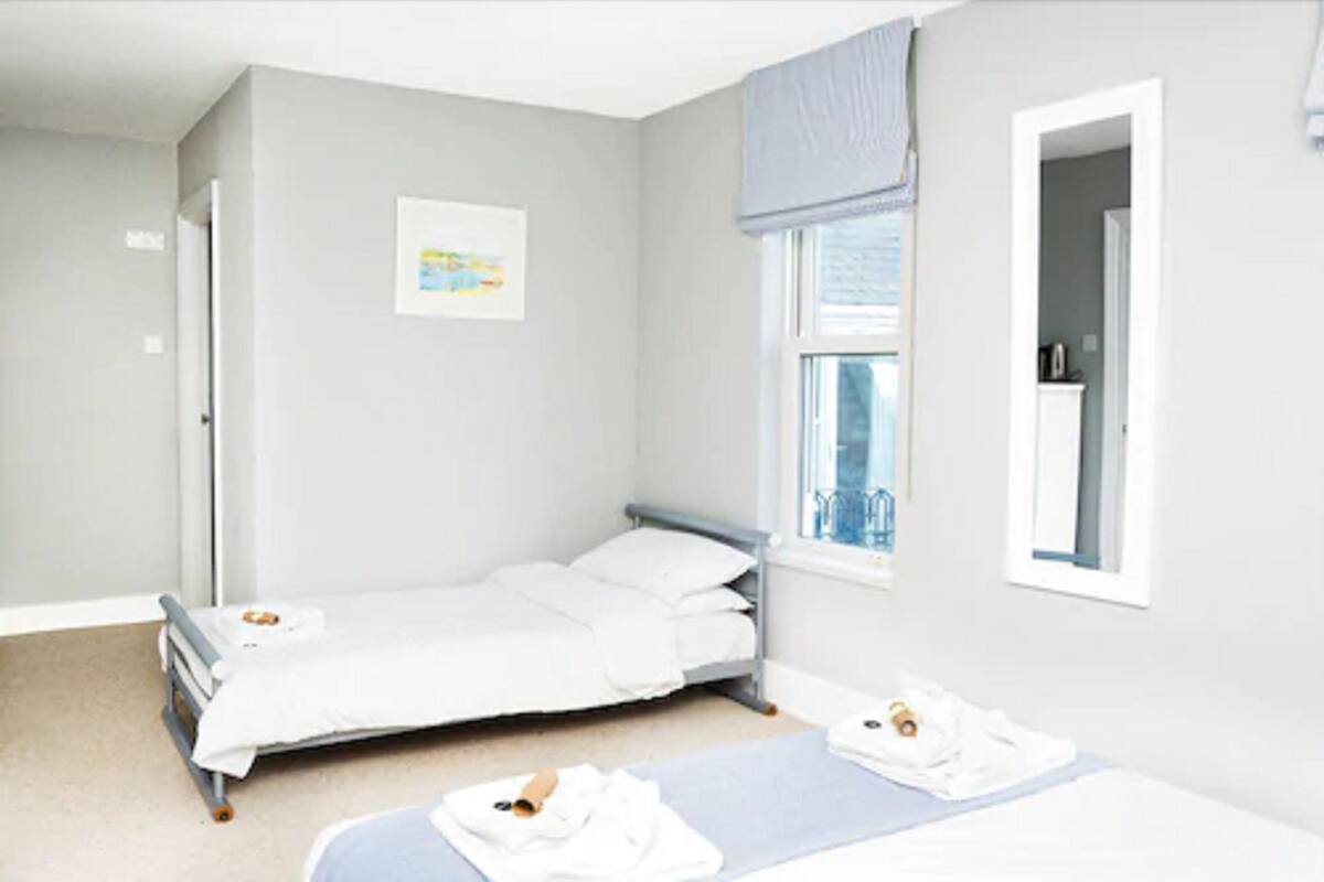 A small, clean room with a single bed, a window with a view, and a door.