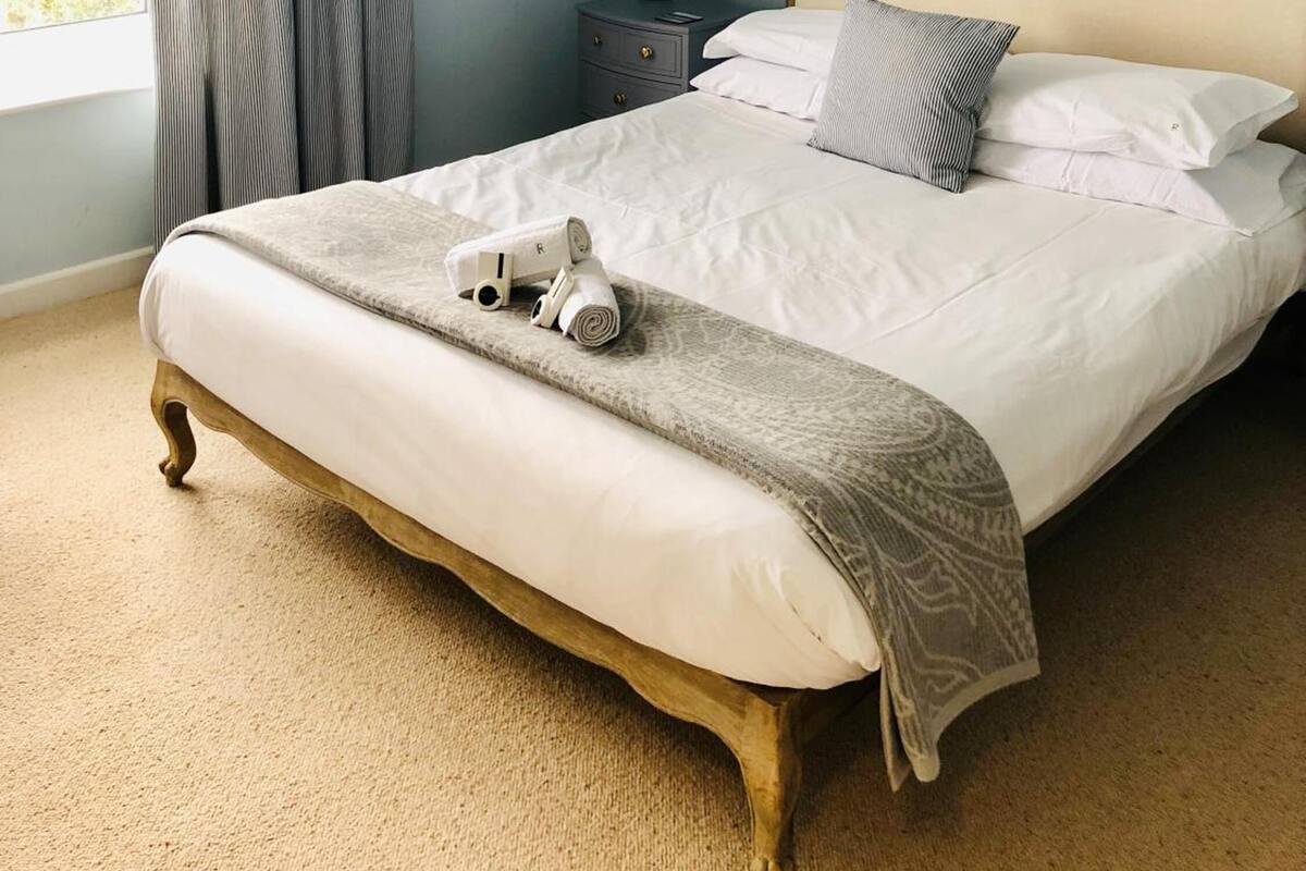 A neatly made bed with a headboard, a bedside lamp, and a towel on the bed.