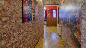 A hallway with brick walls, wooden flooring, and artwork. - Euphoria Inn (Tbilisi)