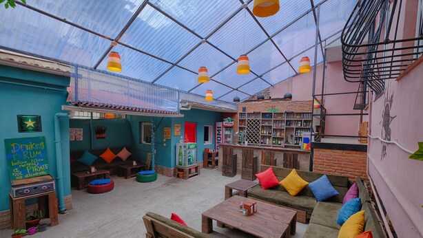 A cozy, open-plan space with wooden furniture, a bar area, and a green wall with a chalkboard sign. - Euphoria Inn (Tbilisi)
