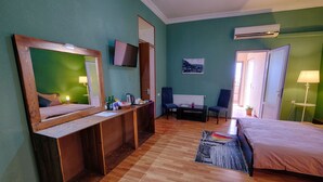 A hotel room with a wooden desk, a bed, a chair, a TV, and an air conditioning unit. - Euphoria Inn (Tbilisi)
