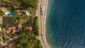 Vista aérea de una zona residencial costera con casas, una playa y una piscina.
