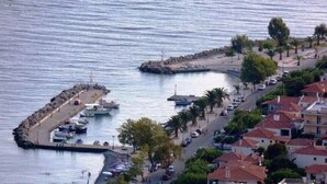 Un pueblo costero con un puerto deportivo, barcos amarrados y edificios con tejados rojos.