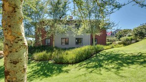 A modern two-story house with a brick facade, surrounded by lush greenery and a well-maintained lawn. - Jackal Creek Self-Catering Apartments (Roodepoort)