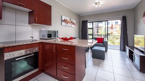 A modern kitchen with a built-in oven, microwave, and granite countertop. - Jackal Creek Self-Catering Apartments (Roodepoort)