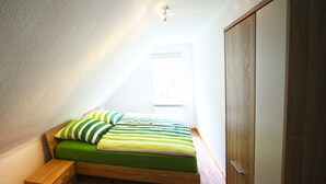 A bedroom with a loft bed, wooden flooring, a window, and a wardrobe. - FeWo Lerbachtal (Osterode am Harz)
