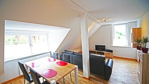 A modern living space with a dining area, seating, and a TV. - FeWo Lerbachtal (Osterode am Harz)