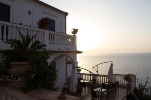 Una terrazza con vista sul mare, con posti a sedere all'aperto e piante in vaso.