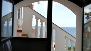 Una habitación con vista a un balcón y al mar.