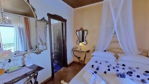 Un dormitorio con cama, tocador con espejo y una mesa con lámpara.